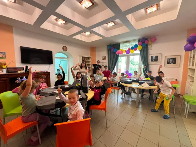 Copii ridicând mâinile la activități, în sala de clasă