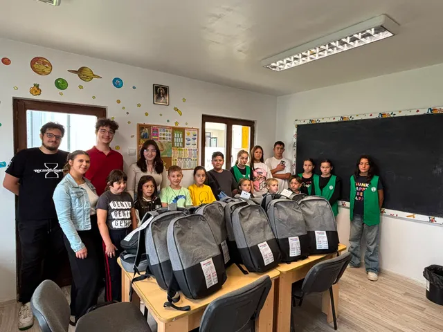 Voluntari și copii lângă ghiozdanele pregătite