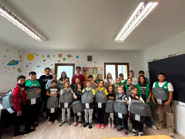 Fotografie de grup cu voluntari și copii cu ghiozdane