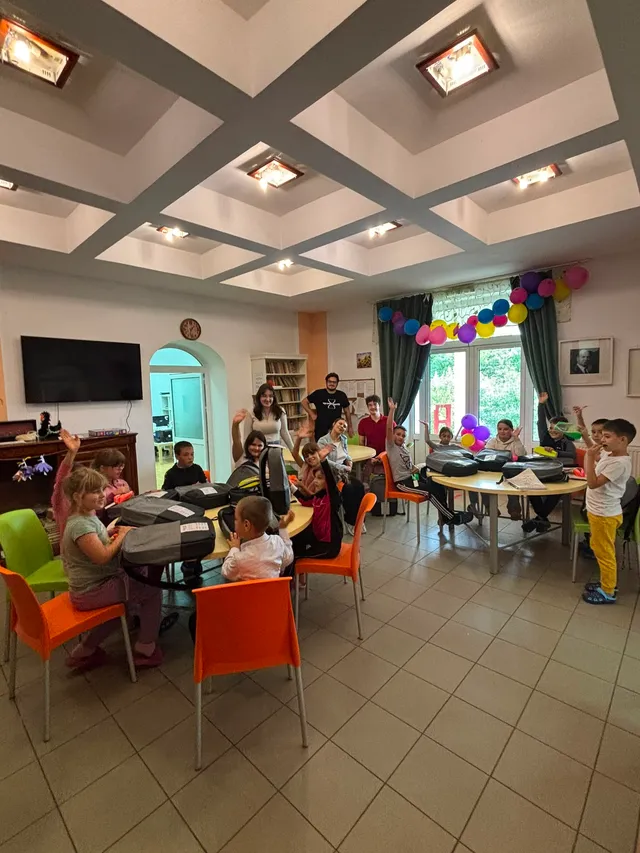 Voluntar alături de copii la masa de activități