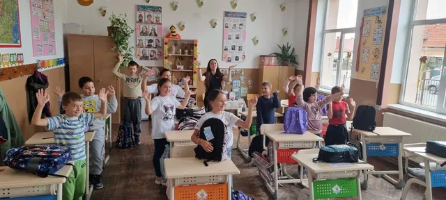 Voluntarii împart ghiozdanele în sala de clasă
