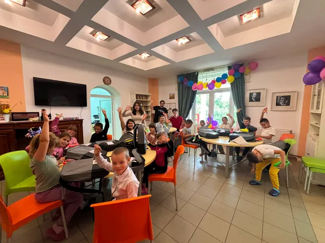 Copii la mese, în sala decorată cu baloane