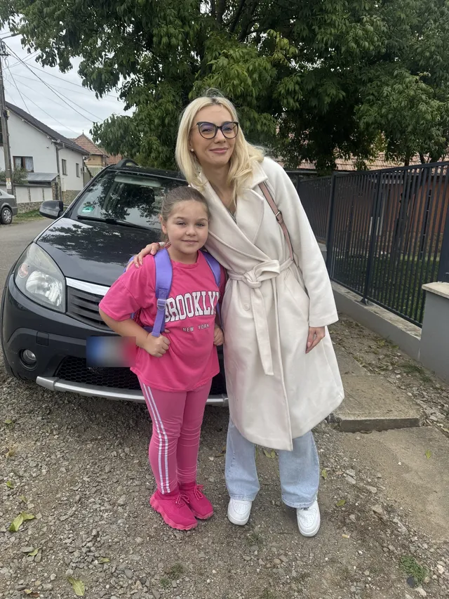 O voluntară alături de o fetiță cu ghiozdanul ei nou